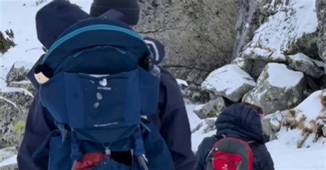 Fotografia turistického nosiča (krosničky) s dieťaťom na chrbte rodiča v horskom prostredí.