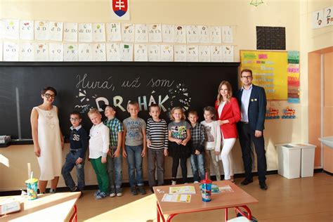 Ilustrácia dieťaťa pripraveného na prvý školský deň, s učiteľkou a rodičmi